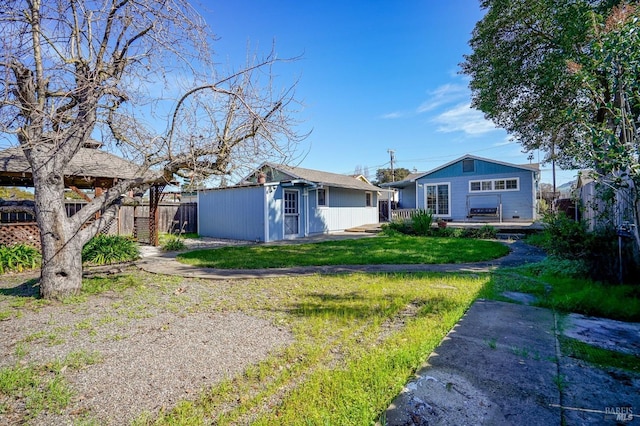 rear view of property with a yard, fence, and an outdoor structure