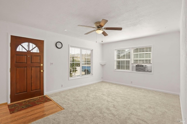 carpeted foyer entrance featuring ceiling fan, a textured ceiling, baseboards, and cooling unit