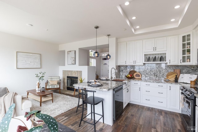 kitchen with a peninsula, black range with electric stovetop, white cabinetry, backsplash, and dishwasher