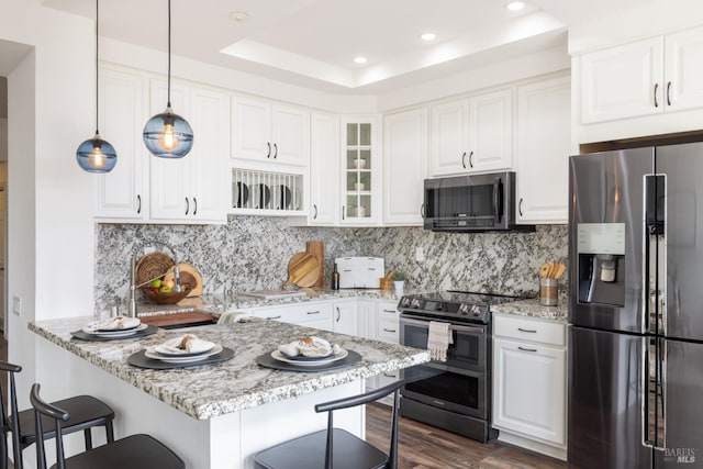 kitchen with light stone counters, appliances with stainless steel finishes, a breakfast bar area, and white cabinetry