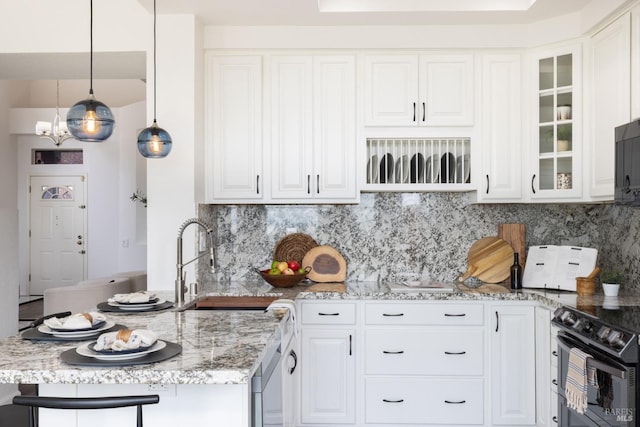 kitchen with black electric range, a peninsula, white cabinetry, and light stone countertops