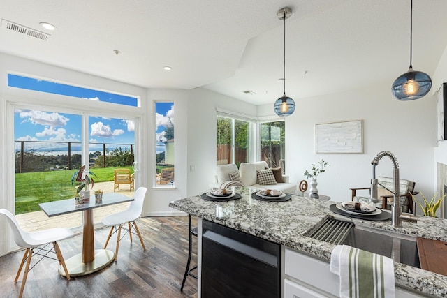 kitchen featuring dark wood finished floors, visible vents, white cabinets, a sink, and light stone countertops