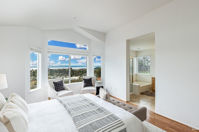 bedroom featuring vaulted ceiling, connected bathroom, baseboards, and wood finished floors