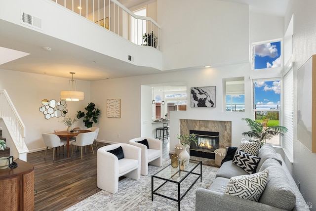 living area featuring stairs, a high end fireplace, visible vents, and wood finished floors