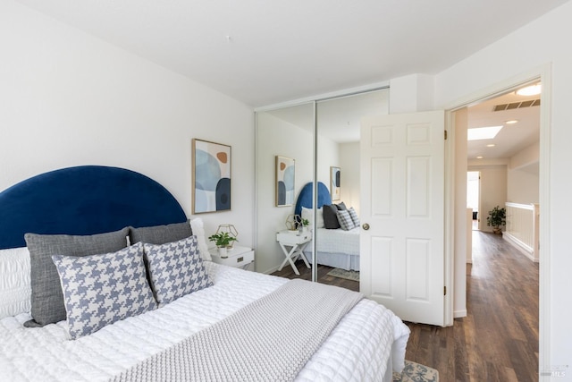 bedroom featuring baseboards, visible vents, a closet, and wood finished floors