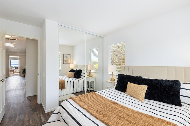 bedroom featuring a closet, wood finished floors, visible vents, and baseboards