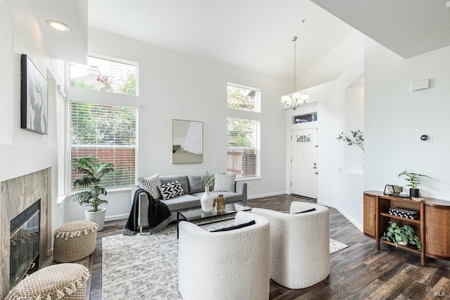 living area with a chandelier, a glass covered fireplace, and dark wood-style flooring