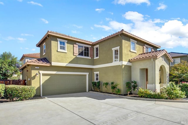 mediterranean / spanish home featuring a garage, concrete driveway, a tile roof, and stucco siding