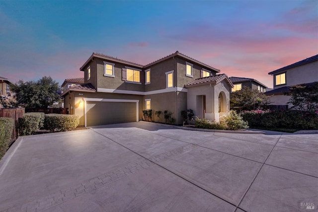 mediterranean / spanish home with a garage, fence, concrete driveway, a tiled roof, and stucco siding