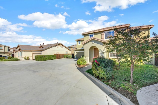 view of front of house with a tile roof, stucco siding, an attached garage, fence, and driveway