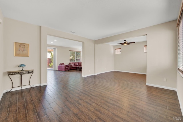 living room featuring dark wood-type flooring, baseboards, and a ceiling fan