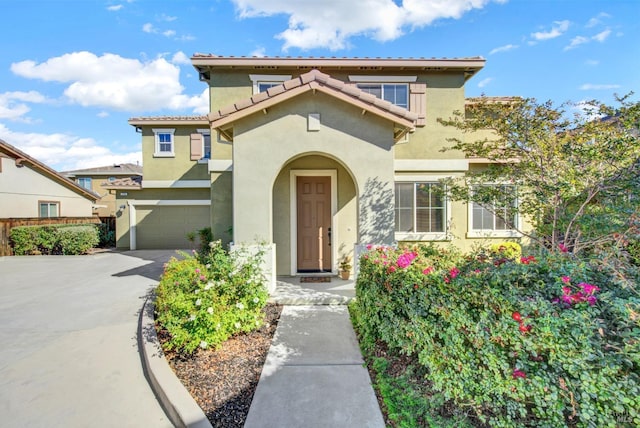 view of front of house featuring a garage, driveway, a tiled roof, and stucco siding