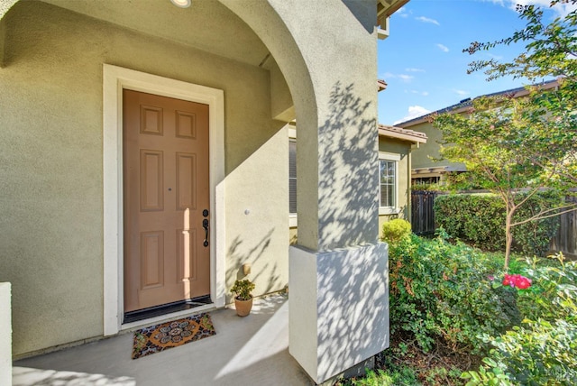 doorway to property featuring fence and stucco siding