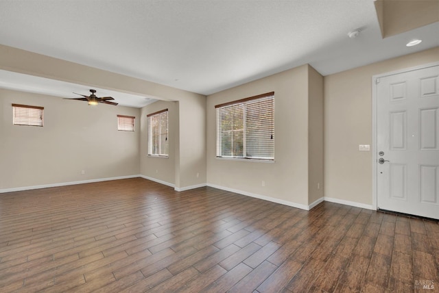 interior space with a wealth of natural light, dark wood-style flooring, ceiling fan, and baseboards