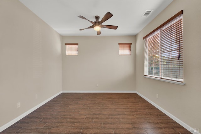 unfurnished room with a ceiling fan, dark wood finished floors, visible vents, and baseboards