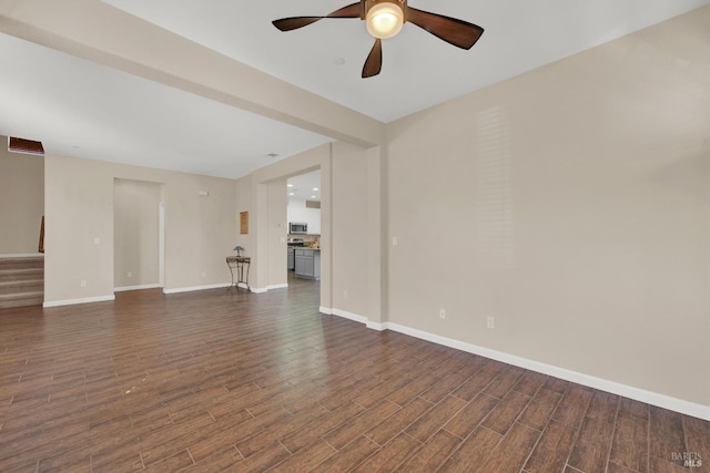 unfurnished living room with ceiling fan, stairs, baseboards, and dark wood finished floors