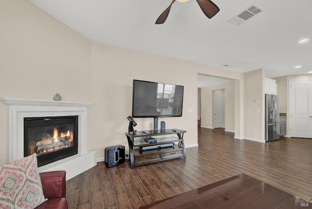 living room with a glass covered fireplace, dark wood-style flooring, visible vents, and baseboards