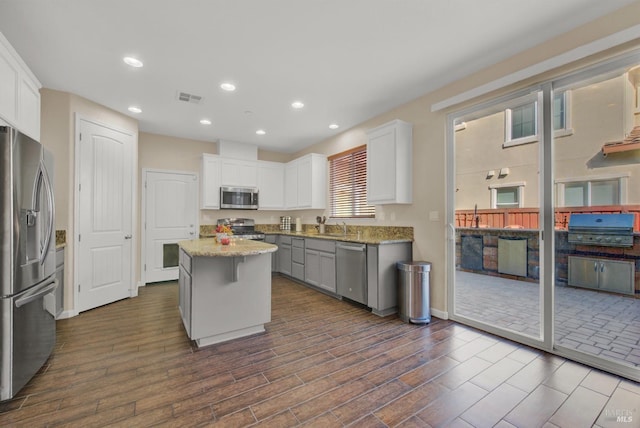 kitchen featuring dark wood-style floors, a center island, stainless steel appliances, visible vents, and white cabinets