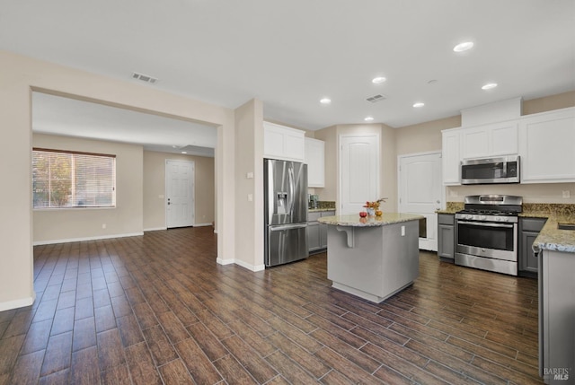 kitchen featuring stainless steel appliances, dark wood-type flooring, visible vents, and a center island