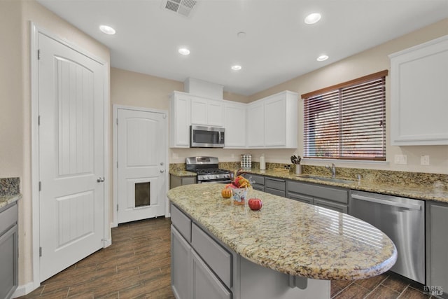 kitchen with light stone countertops, wood tiled floor, visible vents, and stainless steel appliances