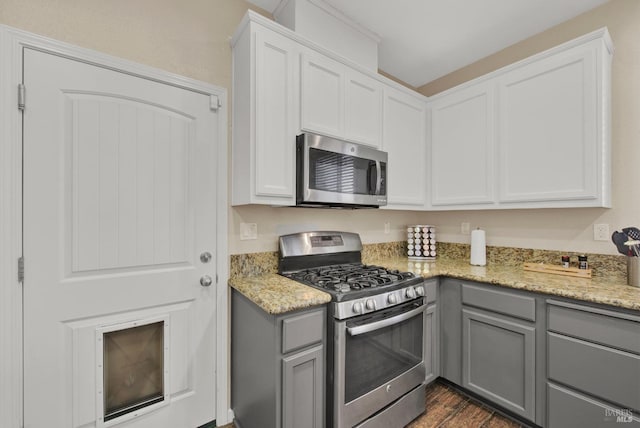 kitchen featuring light stone counters, stainless steel appliances, and gray cabinetry