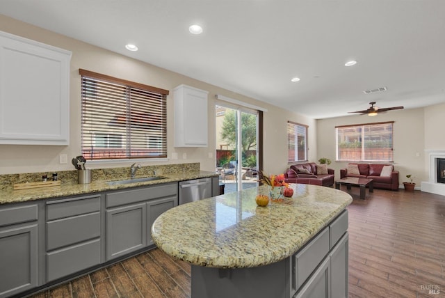 kitchen with dark wood-style floors, gray cabinets, open floor plan, a sink, and dishwasher