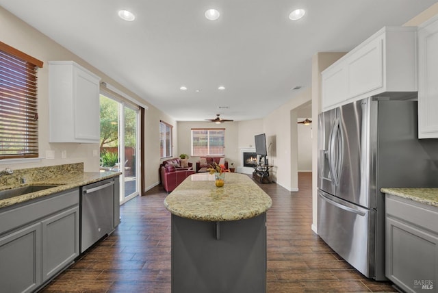 kitchen with appliances with stainless steel finishes, open floor plan, dark wood-type flooring, and a glass covered fireplace