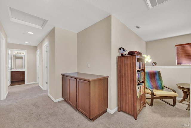 hall featuring attic access, light colored carpet, visible vents, and baseboards