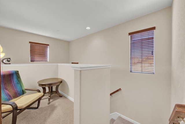 living area with baseboards, carpet flooring, and an upstairs landing