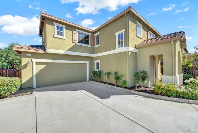 view of front of property featuring a garage, fence, concrete driveway, a tiled roof, and stucco siding