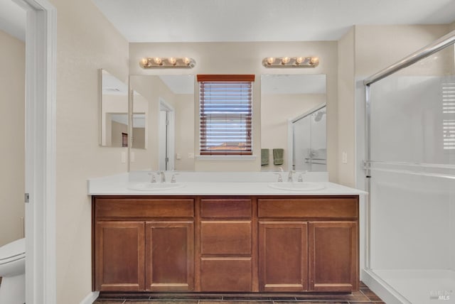 bathroom featuring a sink, a shower stall, and double vanity