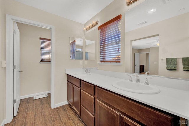 bathroom featuring baseboards, visible vents, a sink, and wood finished floors