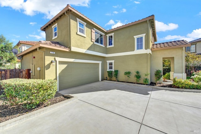 view of front of home with a garage, driveway, a tile roof, fence, and stucco siding