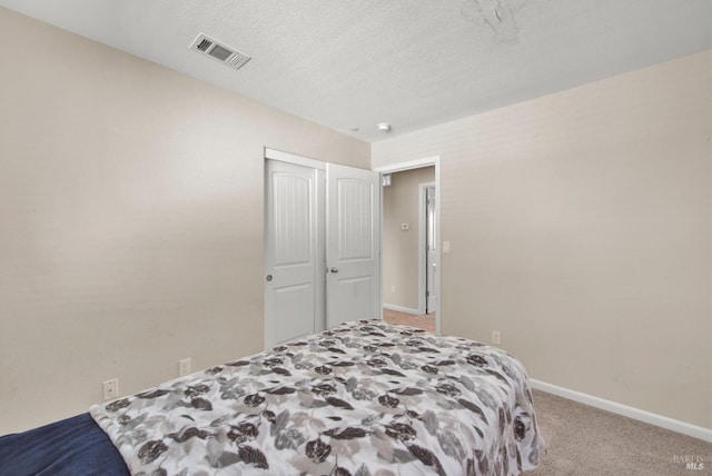 bedroom featuring a closet, visible vents, carpet flooring, a textured ceiling, and baseboards