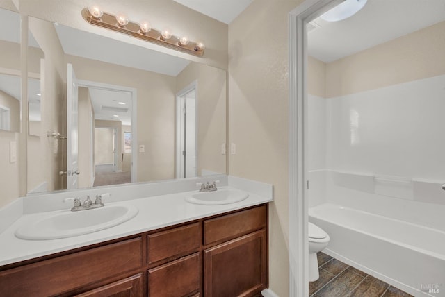 full bath featuring double vanity, a sink, toilet, and a tub