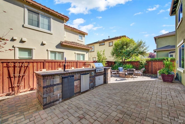 view of patio featuring exterior kitchen, a fenced backyard, and grilling area