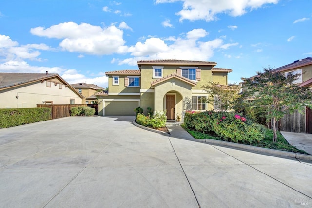 mediterranean / spanish-style house featuring a garage, driveway, fence, and stucco siding