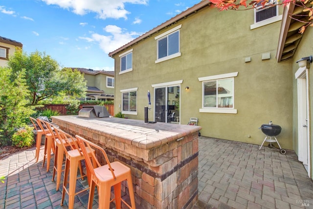 view of patio with exterior kitchen, fence, outdoor wet bar, and a grill