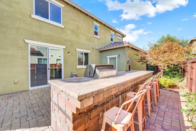 view of patio / terrace with outdoor dry bar, a grill, fence, and an outdoor kitchen