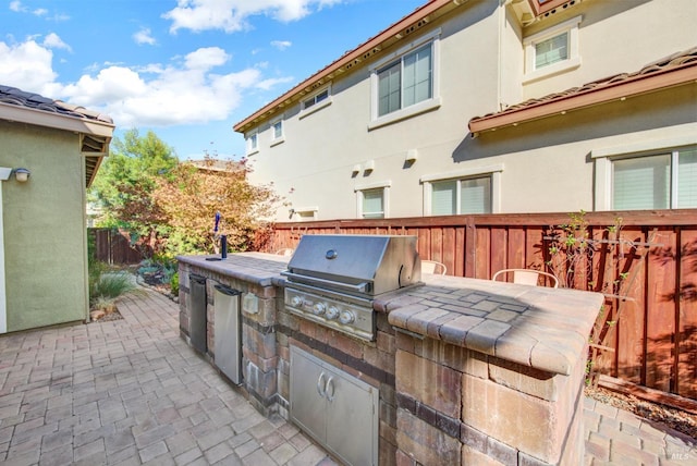 view of patio with an outdoor kitchen, a fenced backyard, and grilling area