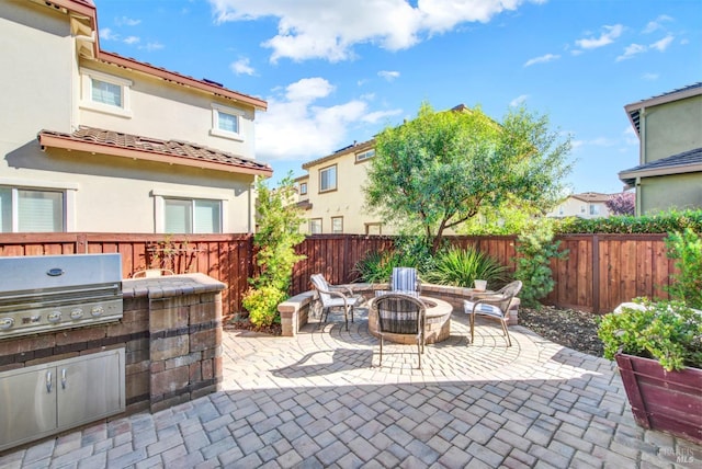 view of patio with a fenced backyard, a fire pit, and area for grilling