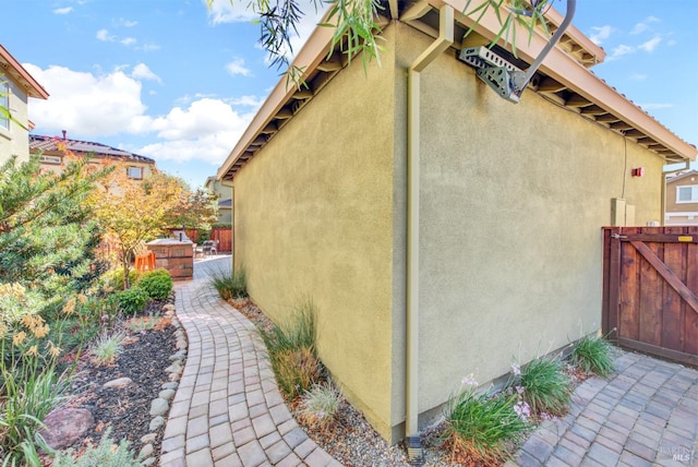 view of side of property featuring a patio area, fence, and stucco siding