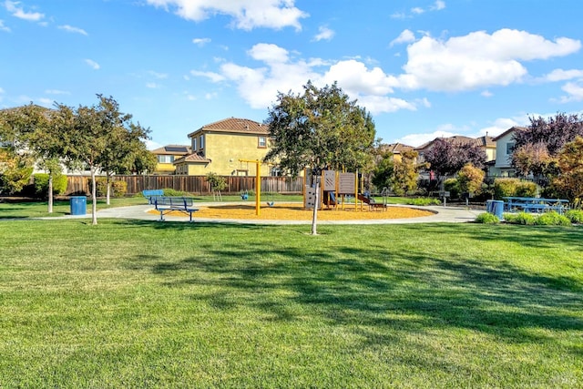 community jungle gym featuring a yard and fence