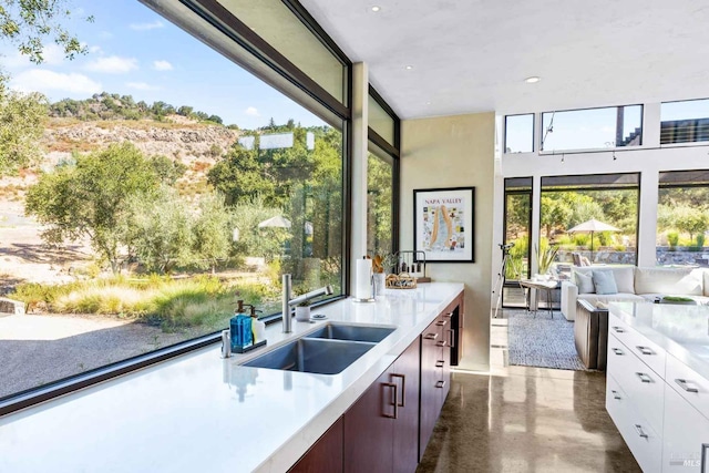 kitchen with light countertops, open floor plan, white cabinets, a sink, and modern cabinets