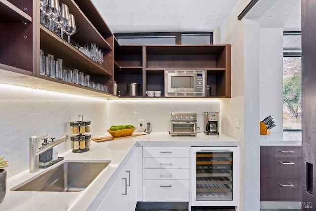 bar with tasteful backsplash, wine cooler, stainless steel microwave, and a sink