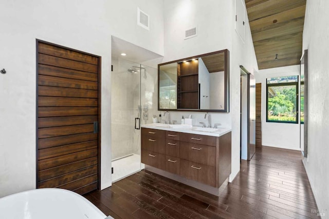 full bath with double vanity, visible vents, a stall shower, a sink, and wood finished floors