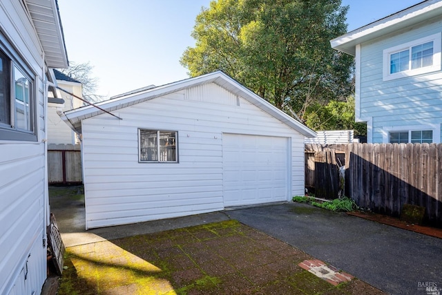 detached garage featuring aphalt driveway and fence