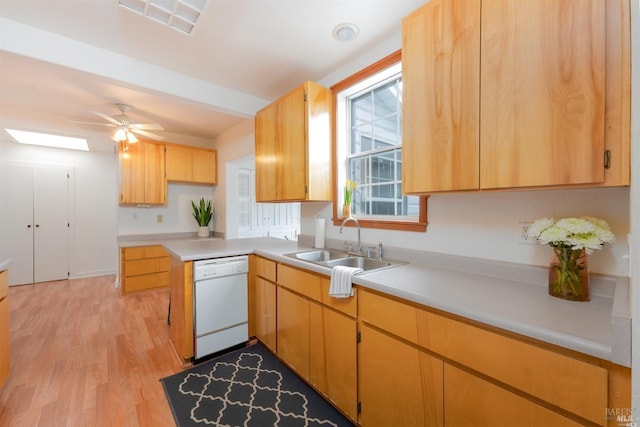 kitchen with a skylight, light countertops, light wood-style floors, a sink, and dishwasher