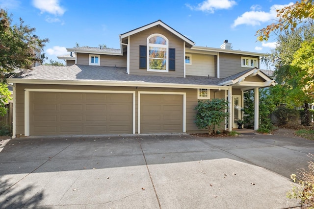 view of front of house with roof with shingles and driveway