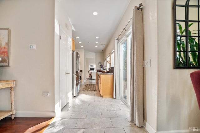 corridor featuring light tile patterned floors, baseboards, and recessed lighting